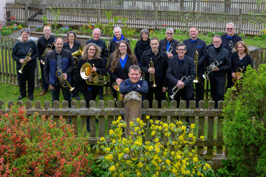 Gruppenbild mit den Instrumenten, Bläserinnen und Bläsern von BlackRiverBrass und ihrem Dirigenten